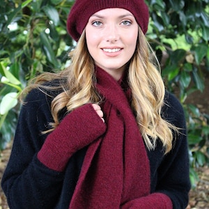 Peut inclure: Ensemble de bonnet, écharpe et mitaines sans doigts en tricot bordeaux. L'ensemble est fait d'un matériau doux et chaud, idéal pour les températures froides.