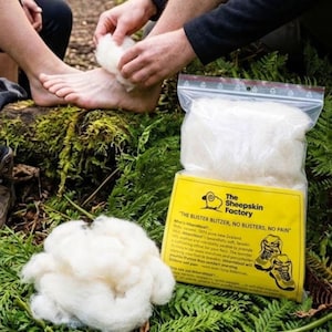 May include: A clear plastic bag containing white New Zealand wool, labeled The Sheepskin Factory with the text The Blister Blitzer, No Blisters, No Pain. A loose pile of the same white wool sits next to the bag, which features a graphic of hiking boots.
