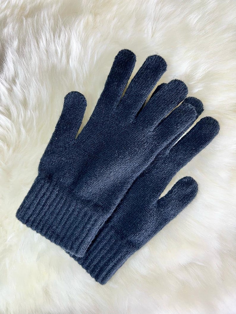 May include: A pair of black knitted gloves with a ribbed cuff. The gloves are made from a soft, warm material and are ideal for keeping your hands warm in cold weather.