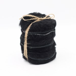 May include: A roll of black wool yarn tied with twine. The yarn is wrapped in several layers and has a fuzzy texture.