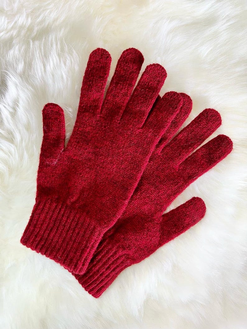 May include: A pair of red knitted gloves with a ribbed cuff. The gloves are made of a soft, warm material and are perfect for keeping your hands warm in cold weather.