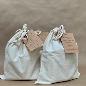 May include: Set of three reusable produce bags made of 100% cotton. The bags are white and have a drawstring closure. The bags are labeled "Reusable Produce Bags" and include sizes: 1 Large bag, 1 Medium bag, and 1 Small bag.