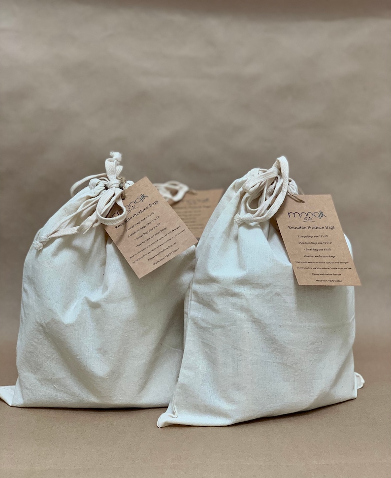 May include: Set of three reusable produce bags made of 100% cotton. The bags are white and have a drawstring closure. The bags are labeled "Reusable Produce Bags" and include sizes: 1 Large bag, 1 Medium bag, and 1 Small bag.