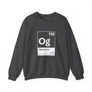 May include: Dark gray sweatshirt with a white periodic table element design. The design features the number 118, the letters "Og", and the name "Oganesson". A casual, long-sleeved crewneck sweatshirt.