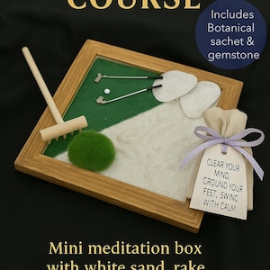 May include: Miniature golf zen garden with a wooden frame, green felt, white sand, and a small rake. Includes a moss ball, golf clubs, and a small bag with a tag that reads "Clear your mind, ground your feet, swing with calm."
