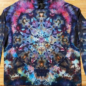 May include: Long-sleeved tie-dye shirt with a symmetrical, floral-like design in shades of blue, purple, pink, and yellow. The shirt has a crew neck and a vibrant, psychedelic pattern. The fabric appears soft and comfortable.