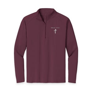 Peut inclure: Un maillot de sport bordeaux à manches longues avec un col montant zippé. Le maillot porte le texte "SWING STATE" au-dessus d'un graphisme blanc d'un club de golf et d'un drapeau. Le maillot est en matière légère et respirante.