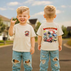 Pode incluir: Camiseta bege de manga curta com um gr&aacute;fico colorido de carros de corrida e o texto "William" na frente. A parte de tr&aacute;s da camisa exibe o texto "Radiator Springs Lightning McQueen" com personagens de carros de desenho animado.
