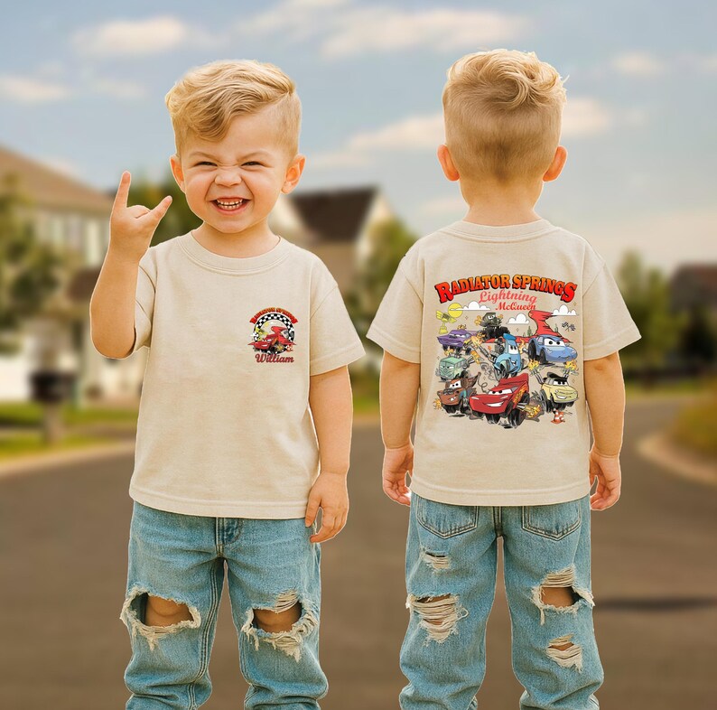Pode incluir: Camiseta bege de manga curta com um gr&aacute;fico colorido de carros de corrida e o texto "William" na frente. A parte de tr&aacute;s da camisa exibe o texto "Radiator Springs Lightning McQueen" com personagens de carros de desenho animado.