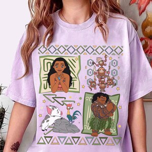 May include: A light purple t-shirt featuring four cartoon panels. The panels depict characters from a movie, including a woman, a group of monkeys, a pig, a rooster, and a man with tattoos. The shirt has a crew neck and short sleeves.