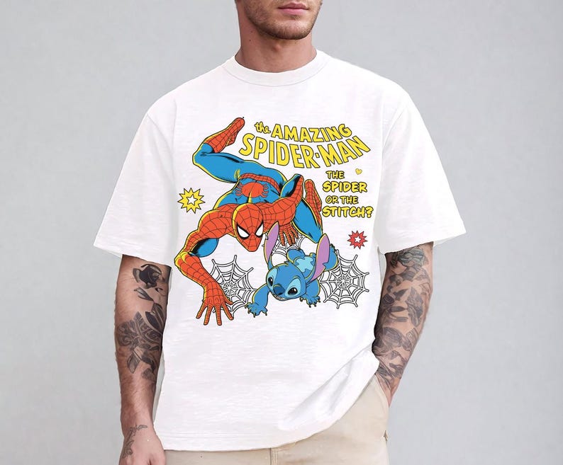 May include: White t-shirt featuring a colorful graphic of Spider-Man and Stitch. The design includes the text "THE AMAZING SPIDER-MAN THE SPIDER OR THE STITCH?" with comic book style elements. The shirt has short sleeves and a crew neck.