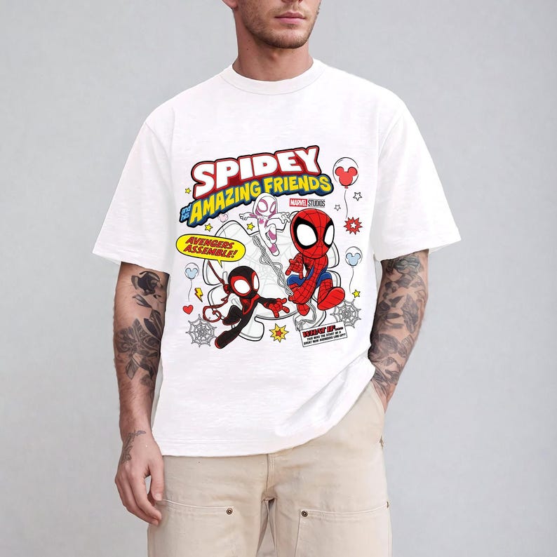 Puede incluir: Camiseta blanca con las palabras "Spidey and His Amazing Friends" e ilustraciones de dibujos animados de Spider-Man, Ghost-Spider y Miles Morales. La camiseta tambi&eacute;n tiene las palabras "Avengers Assemble!" en un recuadro amarillo.