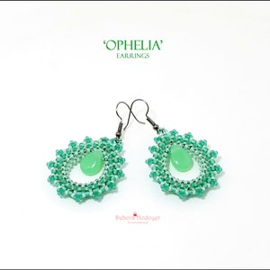 Può includere: Un paio di orecchini 'Ophelia'. Ogni orecchino presenta un design a forma di goccia con un centro di pietra preziosa verde chiaro, circondato da un motivo di perline verdi e bianche. Gli orecchini hanno ganci color argento.