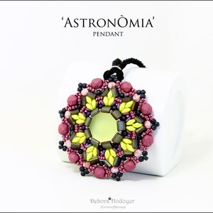 Può includere: Un pendente di perline con il testo "'ASTRONOMÌA' PENDANT". Il pendente presenta una forma centrale verde chiaro circondata da perline gialle, verde scuro, rosa e nere. Il pendente è appeso a un cordoncino nero.