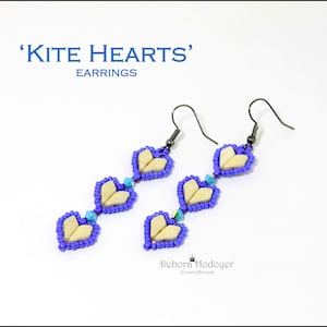Peut inclure: Boucles d'oreilles pendantes avec un motif de cœur. Chaque boucle d'oreille présente trois formes de cœur crème bordées de perles bleues, reliées par des perles bleues et turquoise. Le texte de l'image indique "KITE HEARTS" et "EARRINGS".