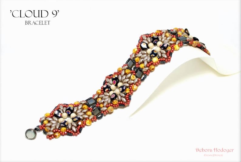 May include: A beaded bracelet with the text "CLOUD 9" and "BRACELET". The bracelet features a pattern of various beads in shades of red, gold, black, and silver. The bracelet is displayed on a white surface.