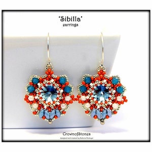 May include: Pair of 'Sibilla' earrings with a floral design. The earrings feature a central light blue crystal surrounded by red, white, and teal beads. The earrings are suspended from silver-coloured hooks.