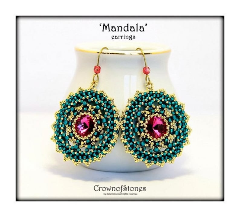 May include: A pair of 'Mandala' earrings. Each earring features a central pink gemstone surrounded by teal beads and gold-colored accents. The earrings hang from gold-colored hooks with small red beads. The text 'Mandala' earrings is at the top.