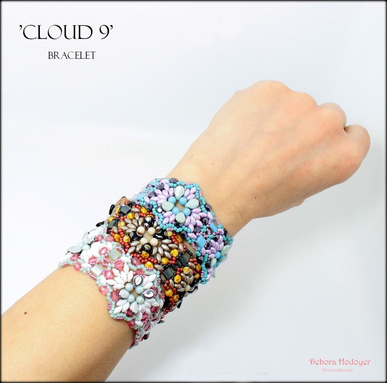 May include: A collection of beaded bracelets in various colors, including white, pink, blue, and brown. The bracelets are adorned with floral patterns and are stacked on top of each other. The text "CLOUD 9" and "BRACELET" are visible in the image.