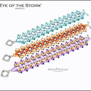 May include: Three beaded bracelets in shades of blue, orange, and purple. Each bracelet features a unique pattern with silver-toned clasps. The top bracelet is light blue and white, the middle is orange and brown, and the bottom is purple and yellow. The text "'EYE OF THE STORM' BRACELET" is at the top.