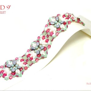May include: A beaded bracelet with the text "CLOUD 9" and "BRACELET" in red. The bracelet features white, pink, and light blue beads. The bracelet is displayed on a white surface.
