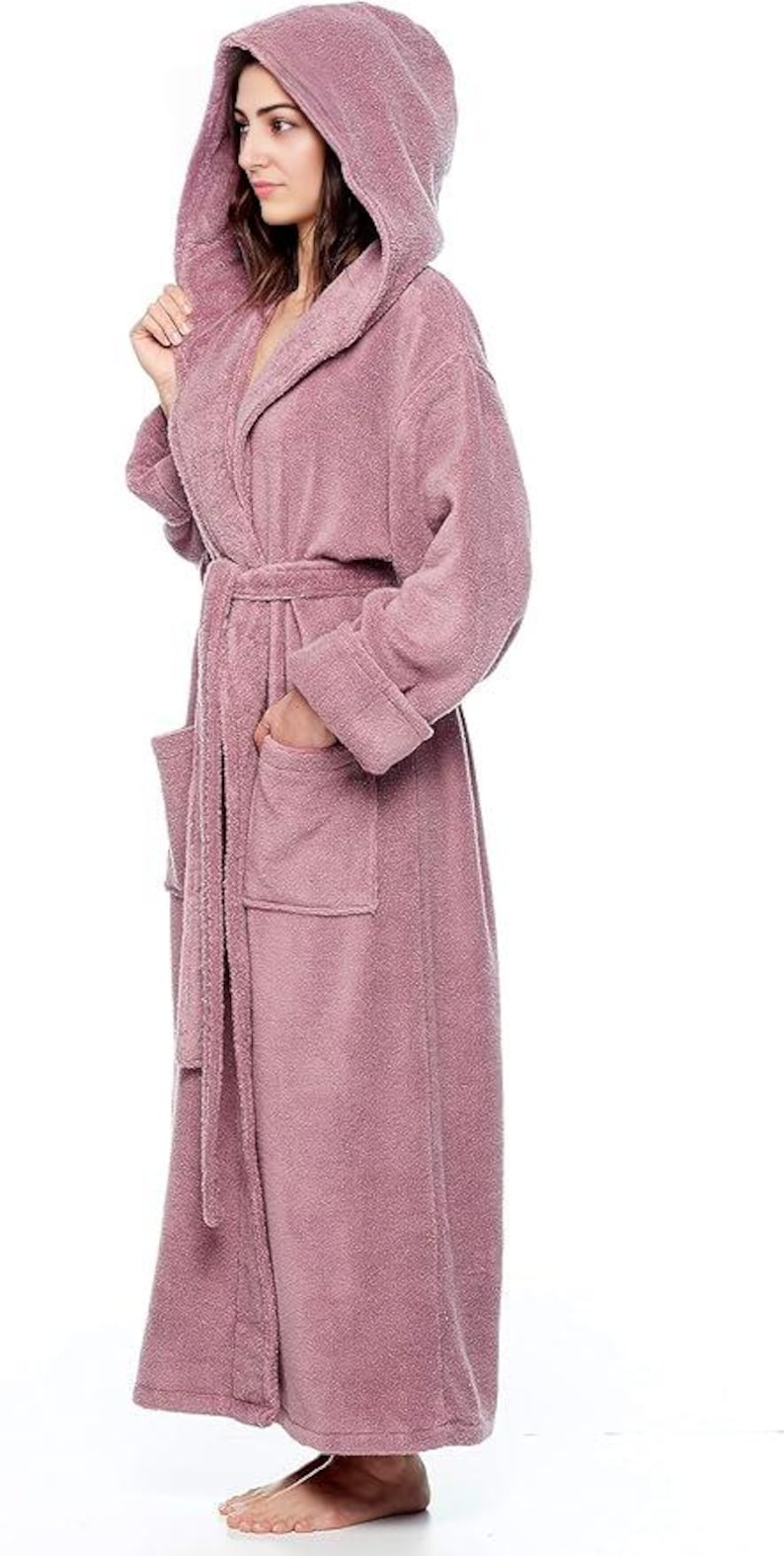 May include: A mauve hooded bathrobe with a matching belt and two front pockets. The plush robe is made of a soft material and has long sleeves. The model is wearing the robe and standing on a white background.