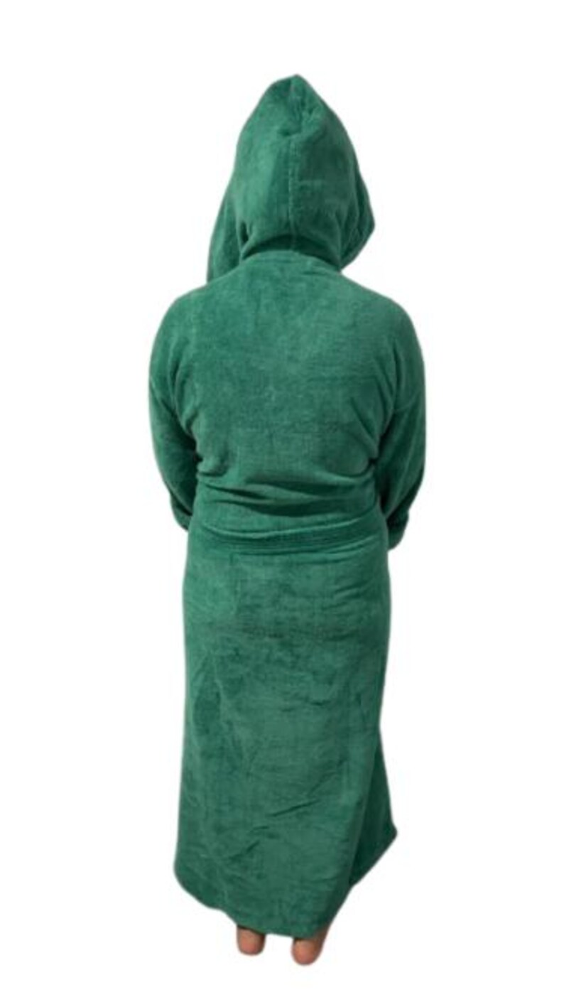 May include: A hooded, emerald green terry cloth robe. The robe has long sleeves and a belt at the waist. The person is facing away from the camera. The robe is made of a soft, absorbent material, perfect for after a shower or a relaxing day.