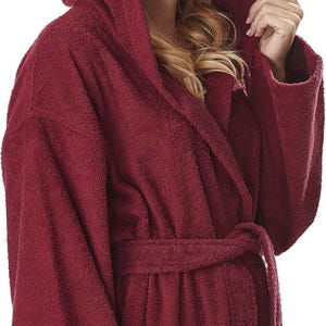 May include: A burgundy hooded bathrobe with a matching belt and pockets. The plush robe is made of a soft, absorbent material, perfect for after a shower or a relaxing day at home.