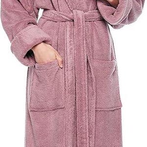 May include: A long, dusty rose-colored hooded robe with a matching belt and pockets. The robe is made of a soft, plush material, perfect for lounging. The model is wearing the robe.