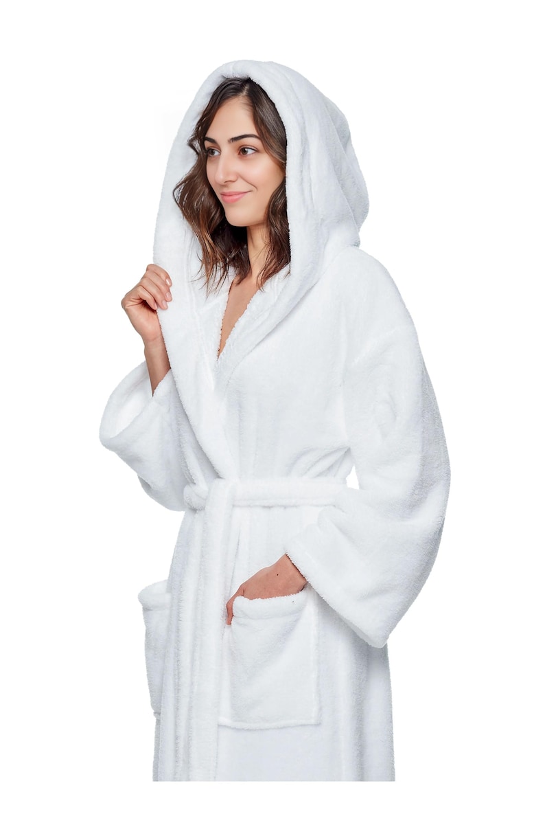May include: A white hooded bathrobe with a matching belt and pockets. The plush robe is made of a soft, absorbent material, perfect for after a shower or a relaxing day at home. The model is wearing the robe.