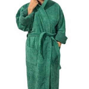 May include: A hooded, emerald green terry cloth robe with a matching belt and pockets. The robe is knee-length and has long sleeves with folded cuffs. The model is wearing the robe.