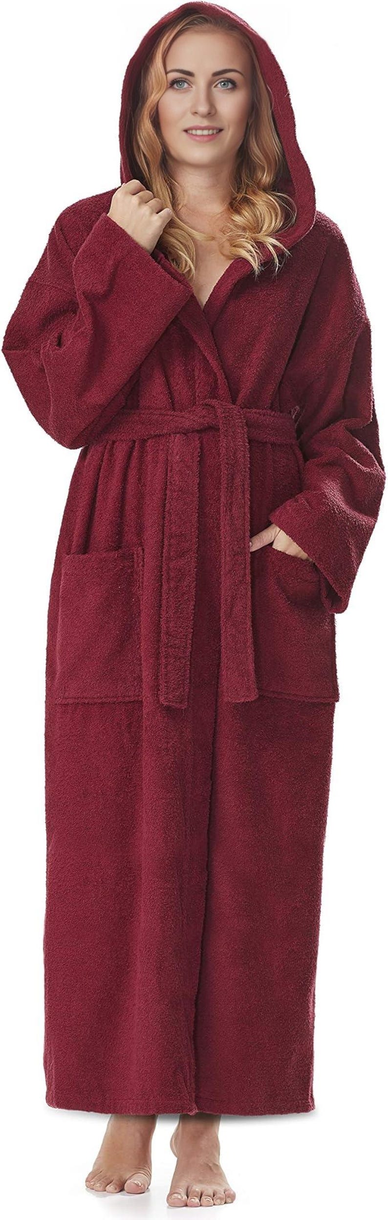 May include: A full-length, hooded burgundy terry cloth robe with a matching belt and pockets. The robe is worn by a person with blonde hair. The robe is made of a soft, absorbent material, perfect for after a shower or bath.