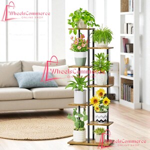 May include: A multi-tiered plant stand with various potted plants. The stand has a dark metal frame and wooden shelves. The plants include green leafy plants, pink flowering plants, and sunflowers. The stand is placed in a living room setting.
