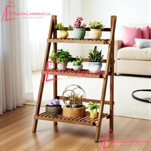 May include: A wooden plant stand with three shelves, displaying various potted plants. The stand is made of light brown wood and has an A-frame design. The plants include succulents, flowering plants, and greenery, adding a touch of nature to the interior.