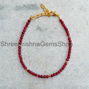 Peut inclure: Un bracelet délicat composé de petites perles facettées rouge foncé, alternées avec de minuscules intercalaires en métal doré. Le bijou est doté d'un fermoir mousqueton en métal doré et d'une chaînette d'extension réglable.