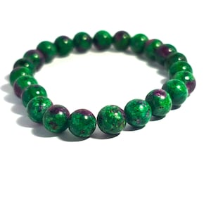 May include: A beaded bracelet featuring round, polished beads in shades of green and maroon. The bracelet is displayed on a white background, showcasing the natural stone's color and texture. A simple, elegant piece of jewelry.
