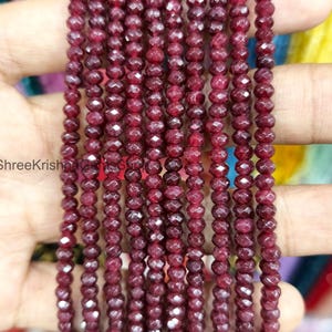 May include: Close-up of multiple strands of deep red gemstone beads. The beads are small, faceted, and uniform in size. They are strung together, creating a continuous line. The beads have a polished, sparkling appearance. The overall effect is a rich, luxurious look.