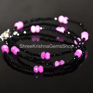 May include: A multi-strand bracelet featuring black beads and vibrant pink gemstones. The bracelet is secured with a silver clasp and is displayed against a dark background. The text "ShreeKrishnaGemsShop" is visible.