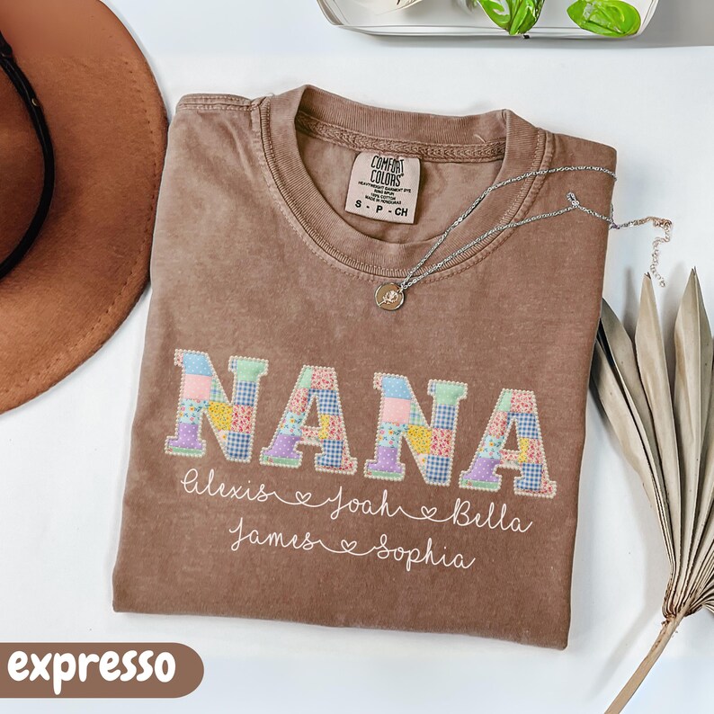 Peut inclure: T-shirt Comfort Colors marron avec le mot "NANA" en lettres patchwork. En dessous, les noms Alexis, Joah, Bella, James et Sophia. Un collier argent&eacute; et un chapeau marron sont &eacute;galement visibles.