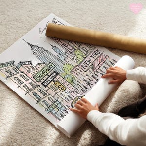 Pu&ograve; includere: Una stampa artistica disegnata a mano di New York City con l'Empire State Building, i cartelli di Broadway e la scritta "New York". La stampa &egrave; arrotolata con un tubo di carta marrone.