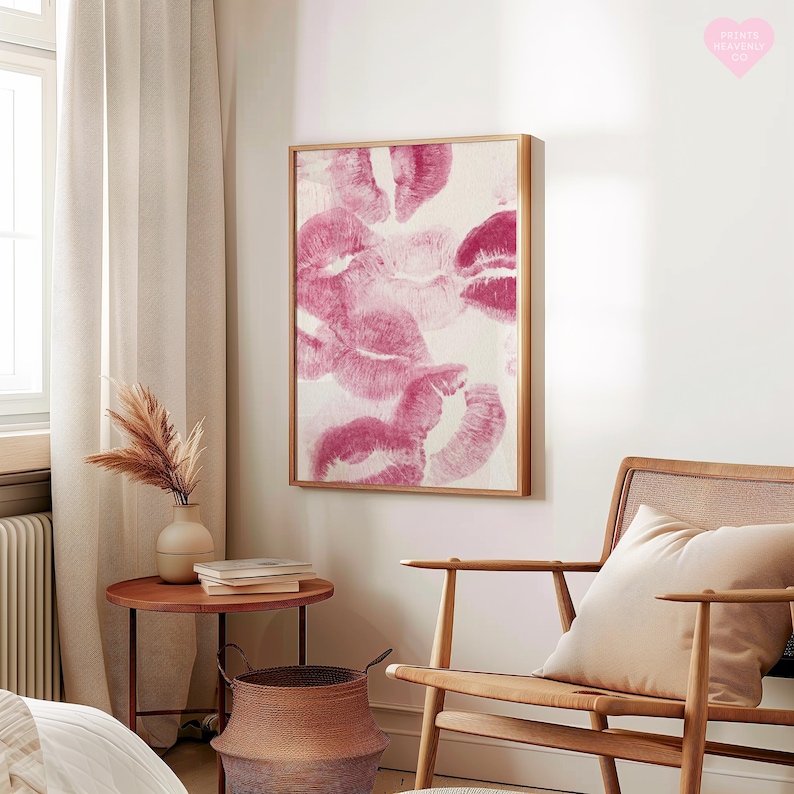 May include: A framed artwork featuring multiple pink lipstick kiss prints on a white background. The artwork is displayed in a room with a wooden chair, a side table, and a woven basket. The overall theme is home decor.