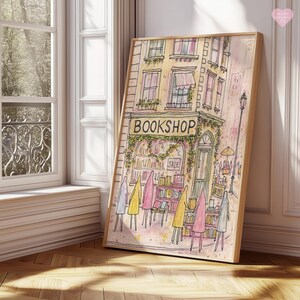 May include: Watercolor print of a bookshop with the word "BOOKSHOP" above the entrance. The artwork features a building with windows, awnings, and a sale sign. Figures in yellow, pink, and gray coats stand in front of the shop. The print is in a wooden frame.