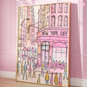 May include: Watercolor print of a New York cafe scene. The artwork features a pink cafe with the text "NEW YORK CAFE" above the entrance. People are depicted walking on the sidewalk and sitting at tables under umbrellas. The buildings are in shades of pink, orange, and yellow.