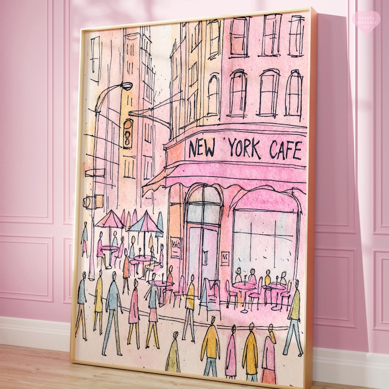 May include: Watercolor print of a New York cafe scene. The artwork features a pink cafe with the text "NEW YORK CAFE" above the entrance. People are depicted walking on the sidewalk and sitting at tables under umbrellas. The buildings are in shades of pink, orange, and yellow.