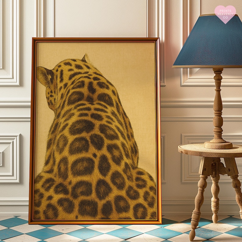 May include: A framed art print featuring a detailed illustration of a leopard's back, showcasing its spotted fur pattern. The artwork is set against a beige background and framed in a dark wood. The print is leaning against a white wall.