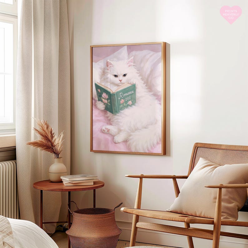 May include: A framed print of a fluffy white cat reading a book titled "Romance 101." The cat is lying on a pink surface with a white pillow. The book is green with pink roses. The frame is a light brown color.