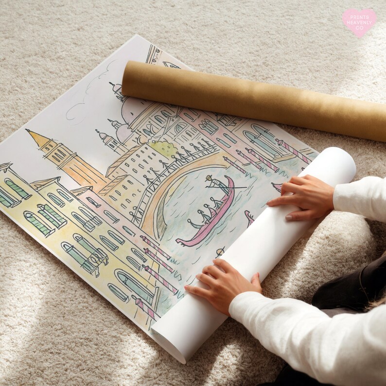 K&ouml;nnte beinhalten: Eine farbenfrohe Illustration von Venedig, Italien, mit einer Gondel, einer Br&uuml;cke und Geb&auml;uden. Das Kunstwerk befindet sich auf einem gro&szlig;en Papierbogen, der teilweise aufgerollt ist, mit einer braunen Papierrolle daneben. Das Bild liegt auf einem wei&szlig;en Teppich.
