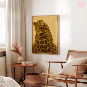 May include: A framed art print featuring a leopard's back, showcasing its spotted fur in shades of brown and black against a golden background. The artwork is displayed in a room with a wooden chair, side table, and a vase with dried plants.