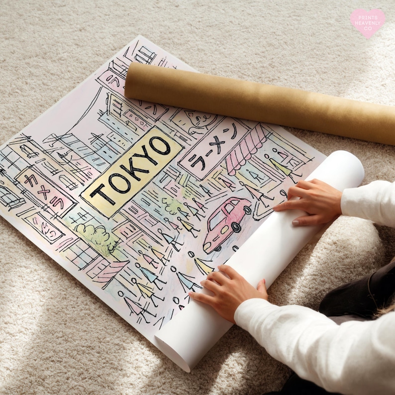 May include: A colorful illustration of Tokyo with the city name in a gold rectangle. The artwork includes Japanese text, a pink car, and figures of people. A rolled-up poster and a brown tube are also visible.