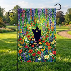 Könnte beinhalten: Gartenflagge mit einer schwarzen Katze mit gelben Augen, umgeben von bunten Blumen in einer lebendigen Gartenszene. Das Kunstwerk zeigt rote Mohnblumen, weiße Gänseblümchen und lila Blauregen.